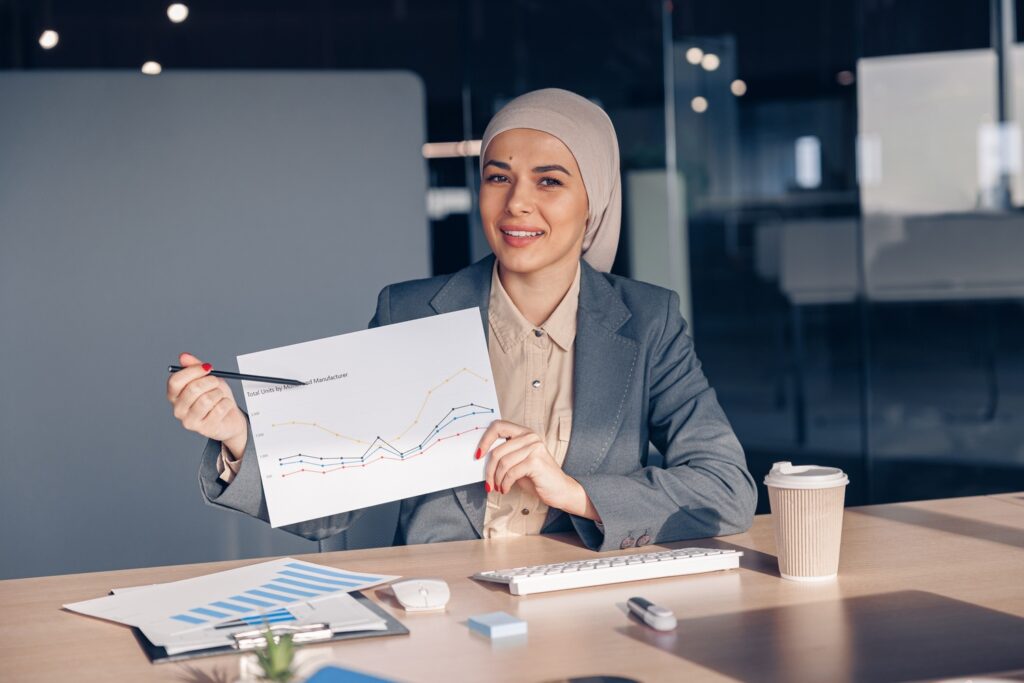 Smiling Muslim Businesswoman In Hijab Shows A Grap AMH74W7 1024x683