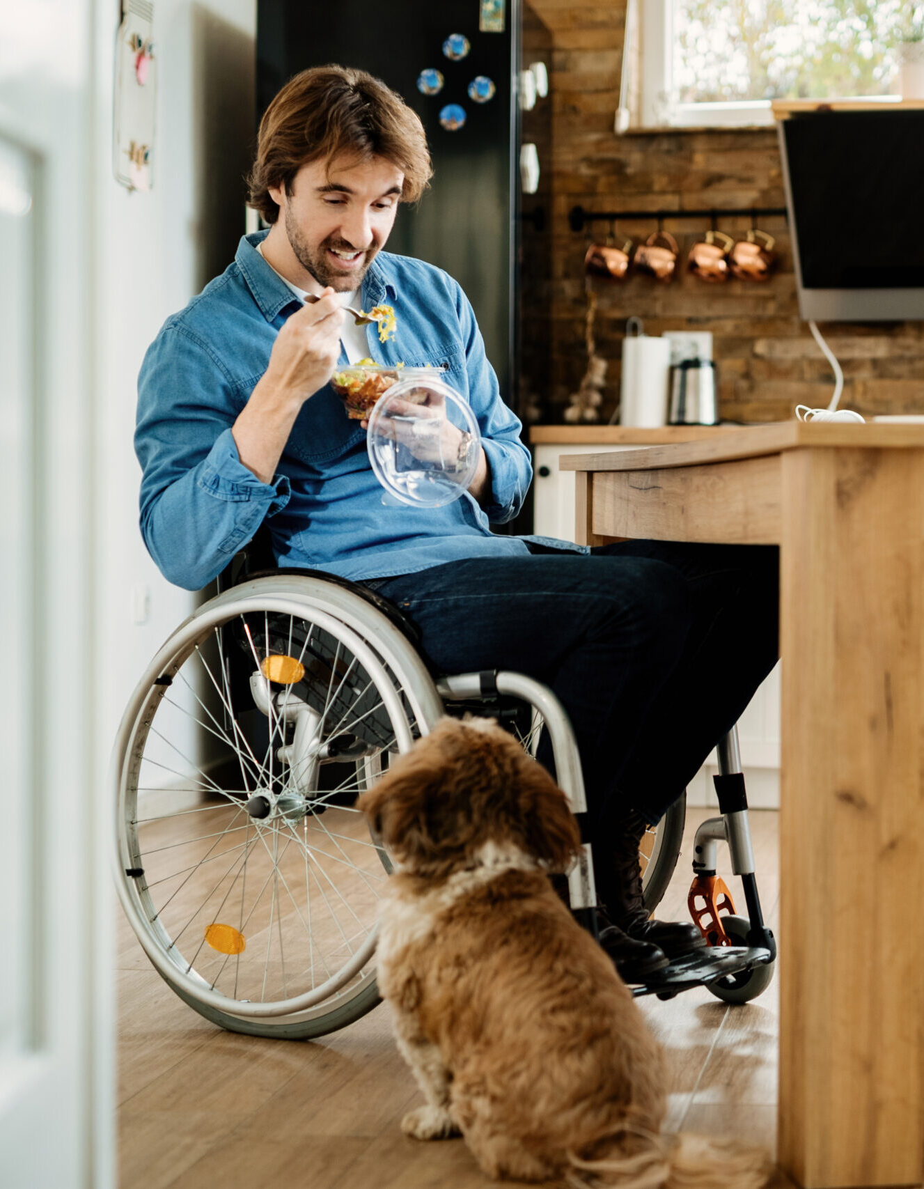happy man in wheelchair eating and communicating with his dog wh